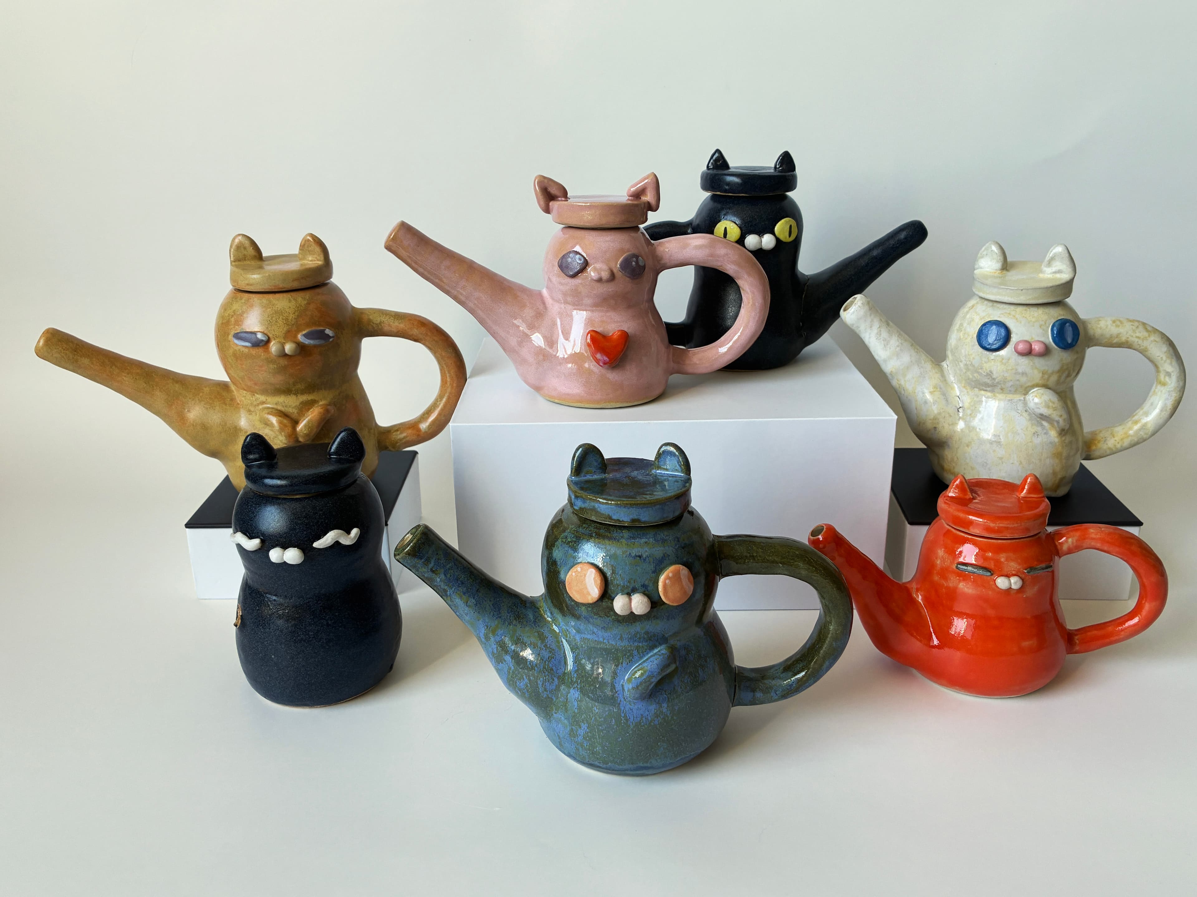 Handmade ceramic teapots with animal-shaped lids arranged in a studio display.